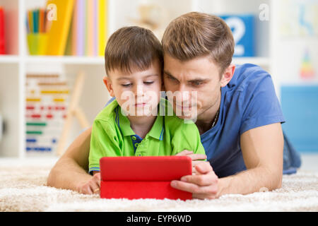 Papà e figlio websurfing sulla tavoletta digitale in casa Foto Stock