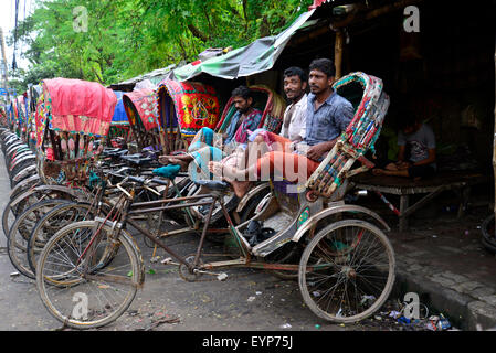 Bengalese driver rickshaw in attesa per i passeggeri di Dhaka. Bangladesh. In luglio, 2015 migliaia di persone dal paese di migrare verso la città capitale Dhaka di lavorare come rickshaw driver come essi non hanno lavoro nei loro villaggi durante i tre a sei mesi di lunga stagione dei monsoni. Ogni rickshaw driver spesso guadagnano meno di US$ 4 al giorno. Foto Stock