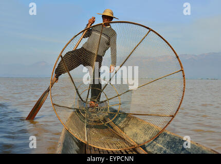 Pescatore intha e la sua tecnica unica di canottare la sua barca con una gamba mentre usando entrambe le mani a fish.Inle Lago, Shan Stato, Myanmar (ex Birmania) Foto Stock