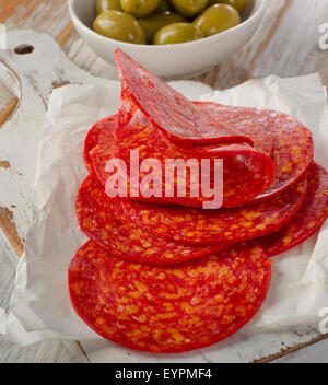 Salsiccia tipo chorizo spagnolo con le erbe su bianco tagliere di legno. Messa a fuoco selettiva Foto Stock