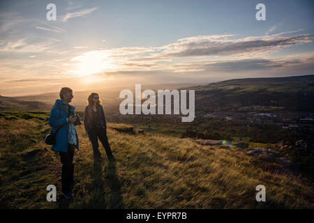 Gli scuotipaglia / Foto Walkers tenendo in vista di Ilkley Moor al tramonto Foto Stock