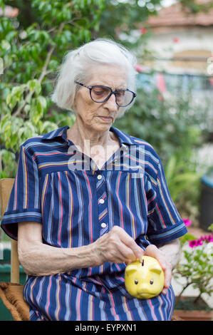 Vecchia nonna Previdenza risparmio di denaro con un salvadanaio Foto Stock