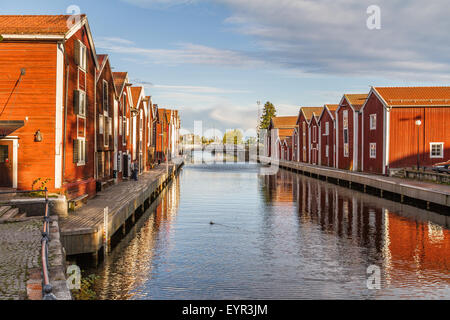 Vecchie casette di pescatori sulla SundsKanal in Hudiksval ,Svezia. Rosso fienile in legno come Cottages riflettendo in Canal Foto Stock