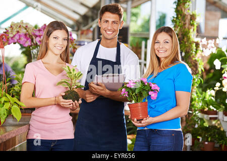 Felice giardiniere gruppo team nel negozio di vivaio con piante e fiori Foto Stock