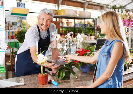 Pagamento mobile nel centro giardino con il venditore e il cliente Foto Stock