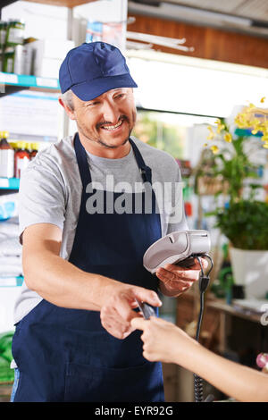 Dando a mano carta di credito per il pagamento alla cassa in vivaio retail store Foto Stock