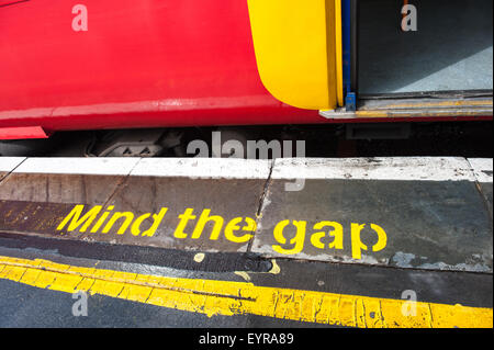 Londra Inghilterra. Colorato treno South West e piattaforma con 'Mind il divario' in giallo. Foto Stock