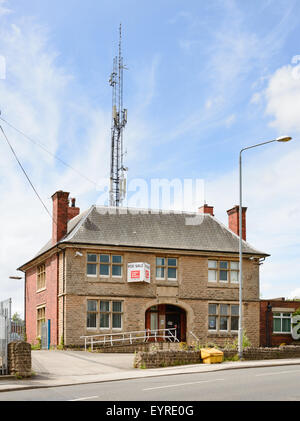 Chiuso e in disuso della stazione di polizia in Kirkby-In-Ashfield, Inghilterra. Dietro, è un telefono cellulare mast macrocella tower Foto Stock