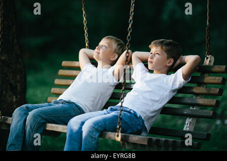 Ragazzi piccoli sognando su swing Foto Stock