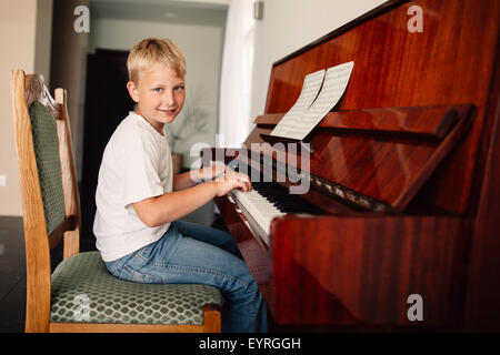 Poco felice ragazzo suona il pianoforte Foto Stock