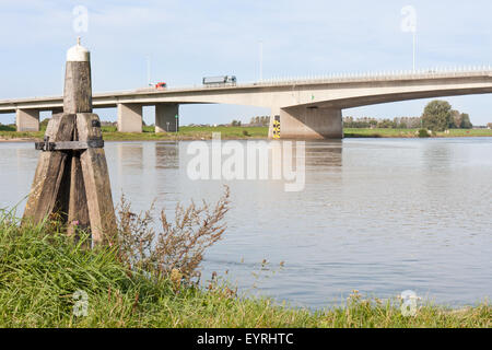 Calcestruzzo ponte che attraversa il fiume IJssel, Paesi Bassi, con un bollard in legno nella parte anteriore Foto Stock