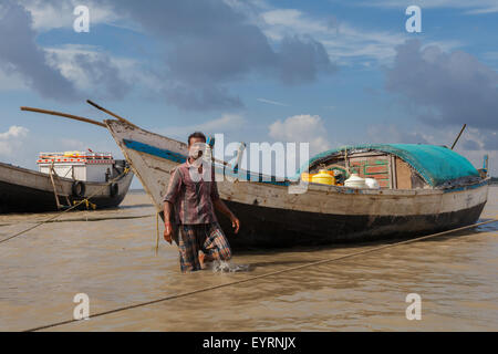 Ritratto di un uomo e di una barca di legno su un porto di fiume della comunità a Haldia, Bengala occidentale, India. Foto Stock