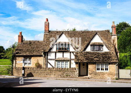 Inghilterra, Lacock, Cotswolds. Grande medievale graticcio e gesso house con tradizionale in bianco e nero British segno posto all'esterno. Foto Stock