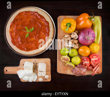 Casa rustica pizza fatta sul tavolo di legno con ingredienti freschi e formaggi Foto Stock