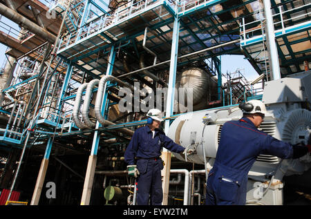 Lavoratori dell'olio all'interno della raffineria di grandi dimensioni Foto Stock