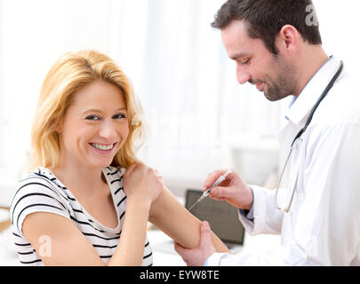 Vista di una giovane donna attraente essendo vaccinato Foto Stock