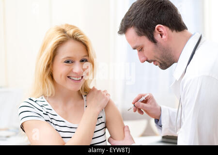 Vista di una giovane donna attraente essendo vaccinato Foto Stock