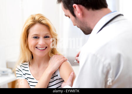 Vista di una giovane donna attraente essendo vaccinato Foto Stock