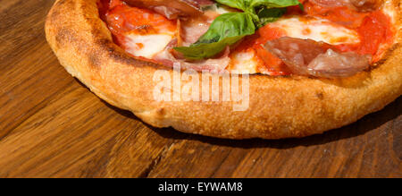 Pizza Fresca su una spessa la pasta su un vassoio in legno Foto Stock