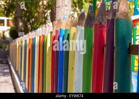 Recinzione di matite colorate al di fuori di una scuola materna. Bella la profondità di campo. Foto Stock