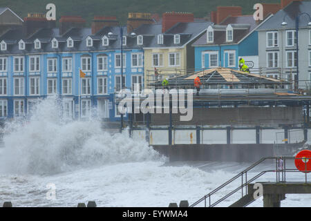 Aberystwyth, Wales, Regno Unito. Il 4 agosto 2015. Le tempeste. Un 5-8 piedi si gonfiano, venti alti e un alta marea si combinano per ancorare Aberystwyth mare con onde enormi, come operai a proseguire i lavori sul lungomare di rivalorizzare bandstand Credito: Alan Hale/Alamy Live News Foto Stock