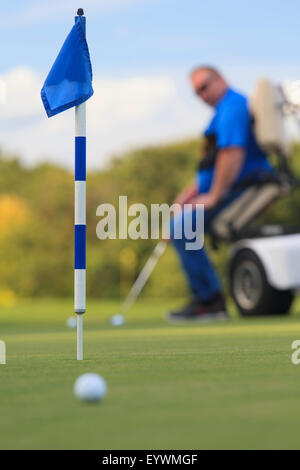 Uomo con una lesione del midollo spinale in un carrello adattabile a golf putting green Foto Stock