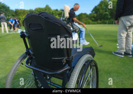 Uomo con una lesione del midollo spinale in un carrello adattabile a golf putting green con un istruttore Foto Stock