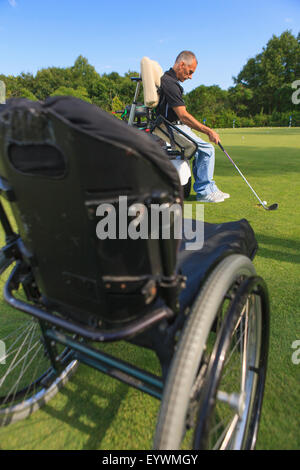 Uomo con una lesione del midollo spinale in un carrello adattabile a golf putting green Foto Stock