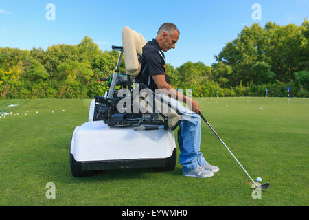 Uomo con una lesione del midollo spinale in un carrello adattabile a golf putting green Foto Stock