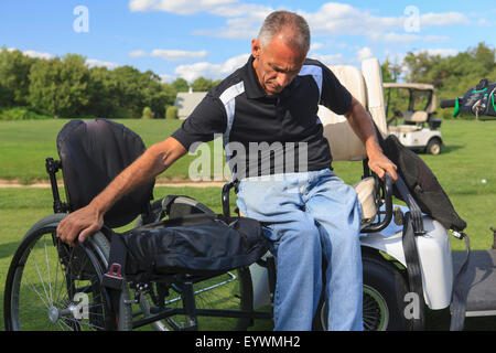 Uomo con una lesione del midollo spinale in un adaptive golf cart per arrivare nella sua sedia a rotelle Foto Stock