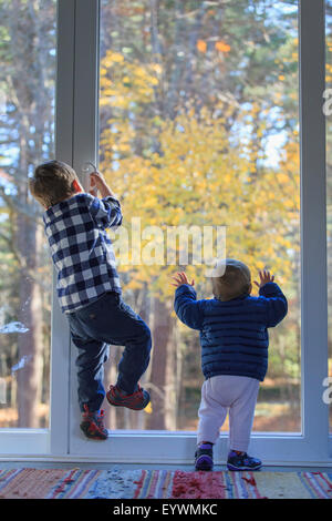 Vista posteriore di un fratello e sua sorella baby arrampicata fuori della porta Foto Stock