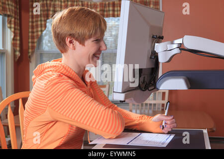 Giovane donna con minorazione visiva lavorando al suo desktop magnifier Foto Stock