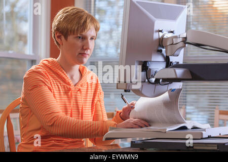 Giovane donna con minorazione visiva lavorando al suo desktop magnifier Foto Stock