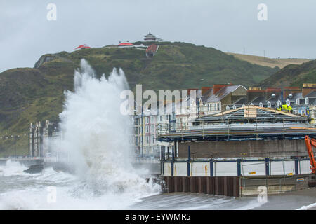 Aberystwyth, Wales, Regno Unito. Il 4 agosto 2015. Le tempeste. Un 5-8 piedi si gonfiano, venti alti e un alta marea cmbine per ancorare Aberystwyth mare con onde enormi, come operai a proseguire i lavori sul lungomare di rivalorizzare bandstand Credito: Alan Hale/Alamy Live News Foto Stock