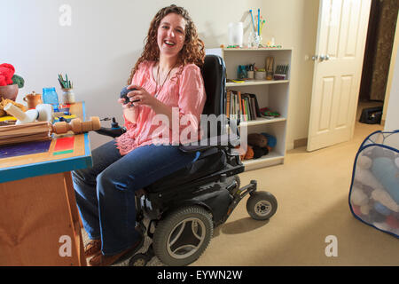 Donna con la distrofia muscolare a lavorare con il suo filo avvolgitore mentre nella sua sedia di potenza Foto Stock