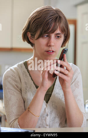 Donna cieca utilizzando la tecnologia assistiva per ascoltare testi sul suo telefono cellulare Foto Stock