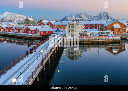 Gli escursionisti ammirare i colori del tramonto sulle tipiche case rosso da un ponte, Svolvaer, Isole Lofoten artico, Norvegia e Scandinavia Foto Stock