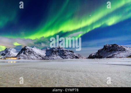 Luci del nord (aurora boreale) illuminano il cielo e le cime innevate, Flakstad, Isole Lofoten artico, Norvegia e Scandinavia Foto Stock