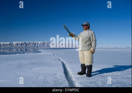 Cacciatori Inuit filo da pesca a bordo floe per merluzzo artico, sculpin e halibut vicino isola Herbert, Groenlandia, Danimarca Foto Stock