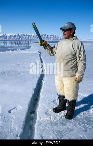 Cacciatori Inuit filo da pesca a bordo floe per merluzzo artico, sculpin e halibut vicino isola Herbert, Groenlandia, Danimarca Foto Stock