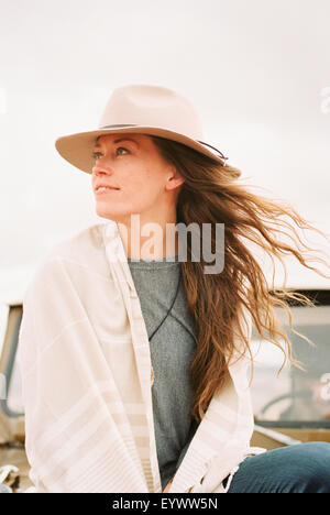 Donna che indossa un cappello seduto sulla parte anteriore di una jeep guardando intorno a lei. Foto Stock