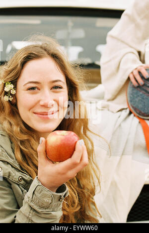 Una giovane donna tenendo fuori un rosso spellati apple. Foto Stock