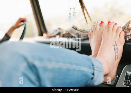 A piedi nudi donna in appoggio i suoi piedi sul cruscotto di un 4x4, un tatuaggio sul suo piede destro. Foto Stock