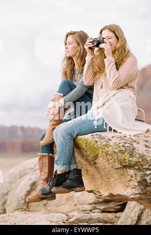 Due donne seduto su una roccia di scattare una foto Foto Stock