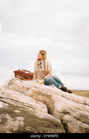 Donna seduta su una roccia con borsa in pelle Foto Stock