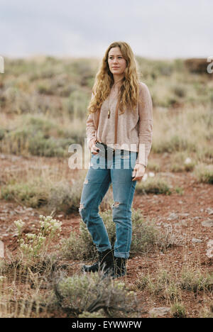 Donna in piedi in un deserto, tenendo una telecamera. Foto Stock