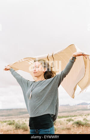 Donna che mantiene un wrap che fluttua nel vento. Foto Stock