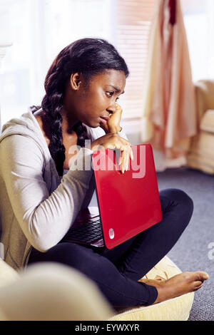 Frustrati di etnia ragazza sedeva in ambienti interni Foto Stock
