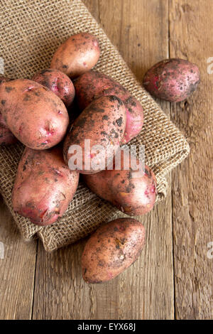 Raw patate organico su tela e tavola in legno rustico Foto Stock