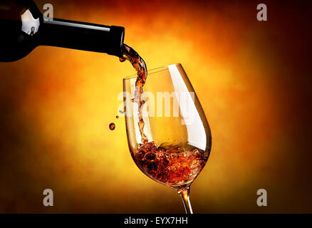 Versare il vino nella Wineglass su uno sfondo arancione Foto Stock